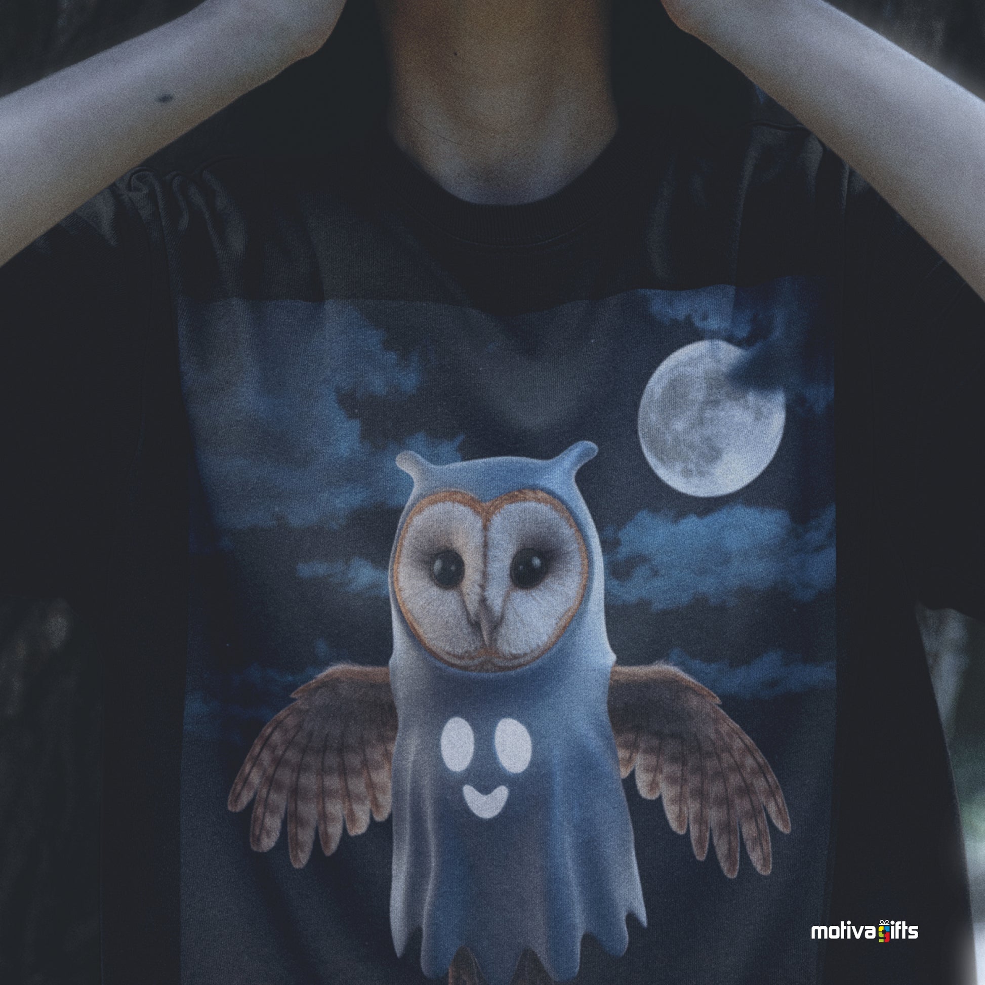 Woman wearing a black Shirt featuring a design of a barn owl dressed in a ghost Halloween costume