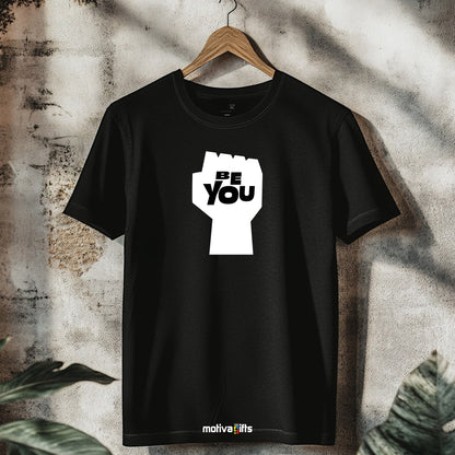 A hanging black T-shirt featuring bold white typography that reads Be You 