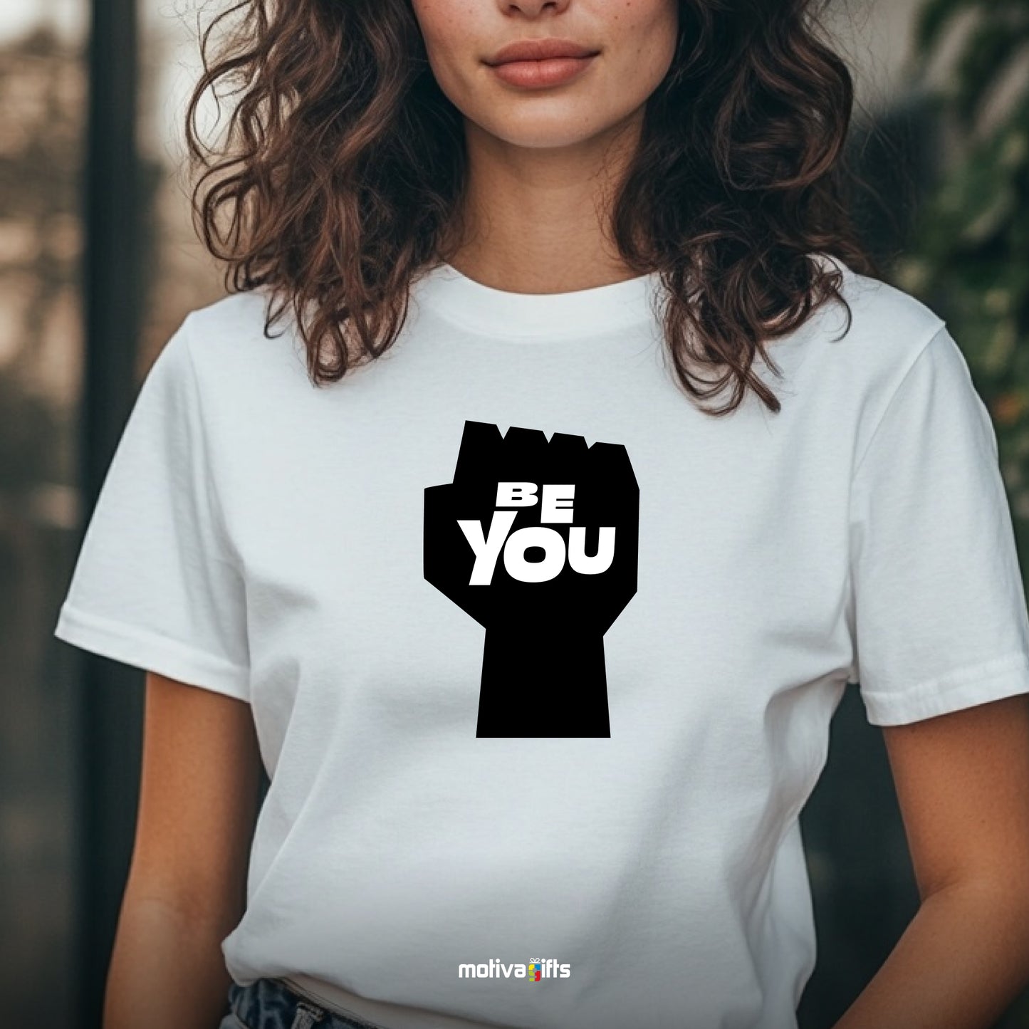 A woman wearing a white T-shirt featuring bold black typography that reads Be You 