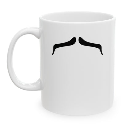 Photo of a white ceramic mug with a drawing of Charles Bronson’s mustache, set against a plain white background.