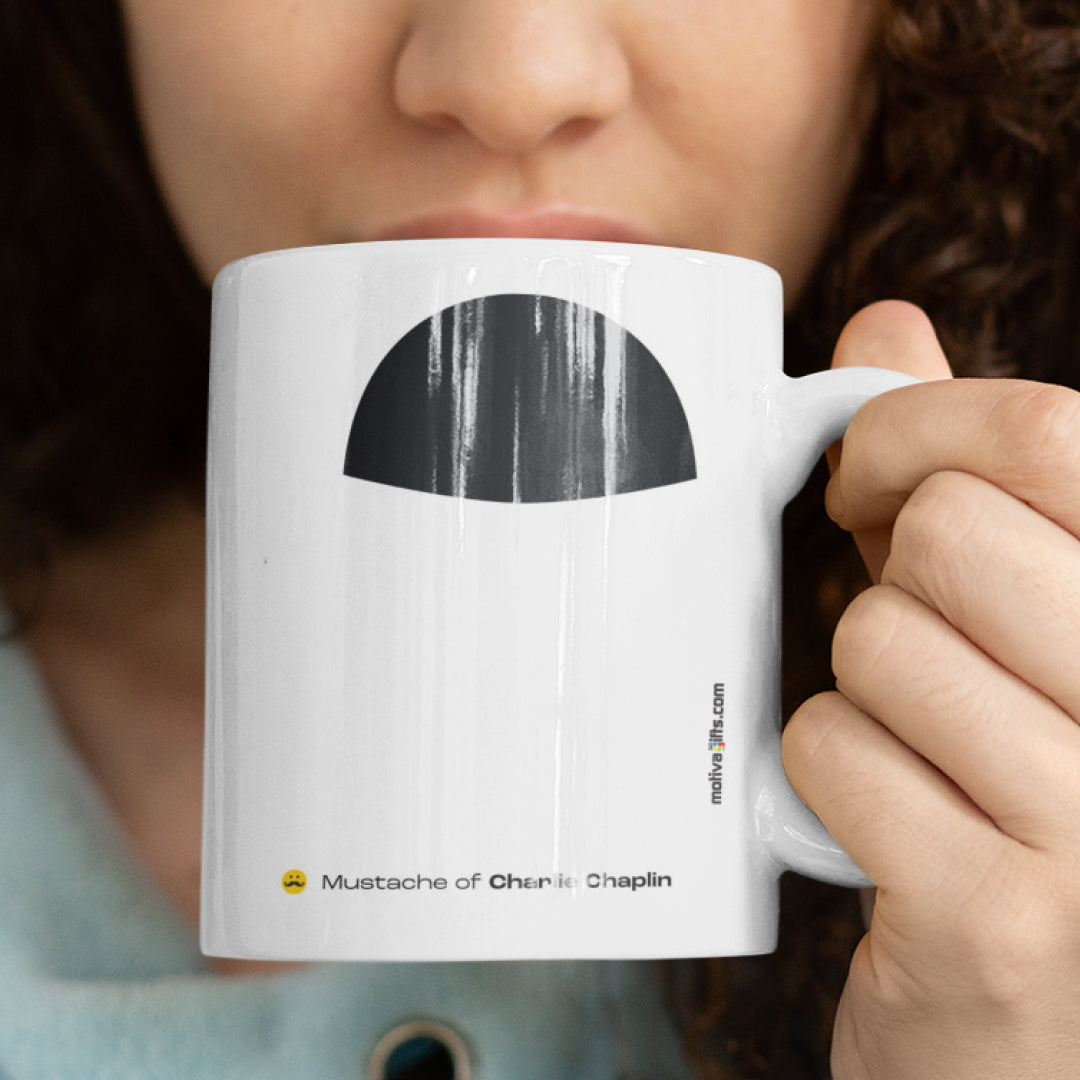 Woman holding a white ceramic mug with a drawing of Charlie Chaplin's mustache