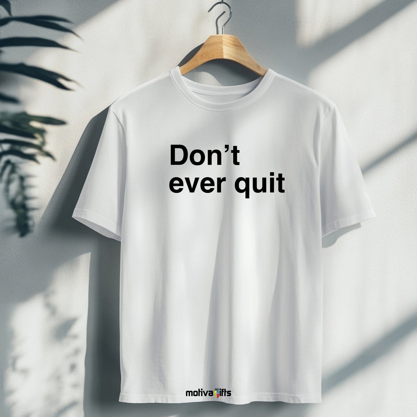 A hanging white T-shirt featuring bold black typography that reads Don’t ever quit 