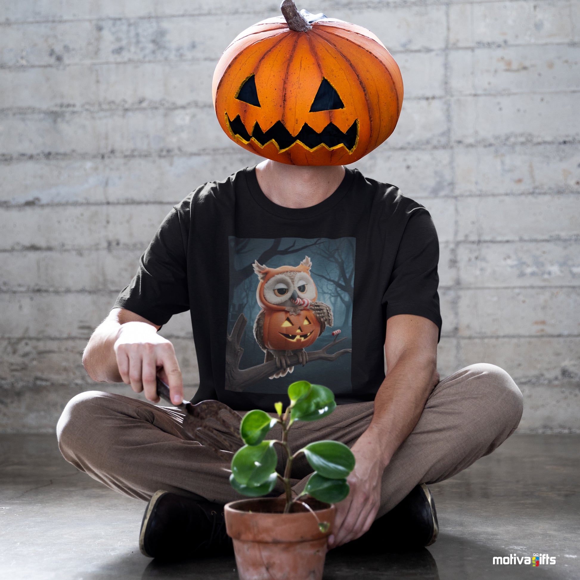 Man wearing a black Shirt featuring a design of a elf owl dressed in a pumpkin Halloween costume eating candy