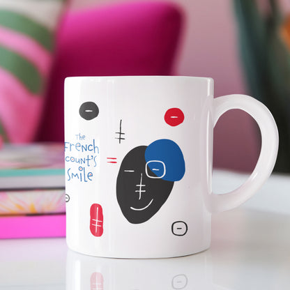 White ceramic mug with a drawing of French Count's Smile Smile Mug featuring a modern table in a relaxing setting