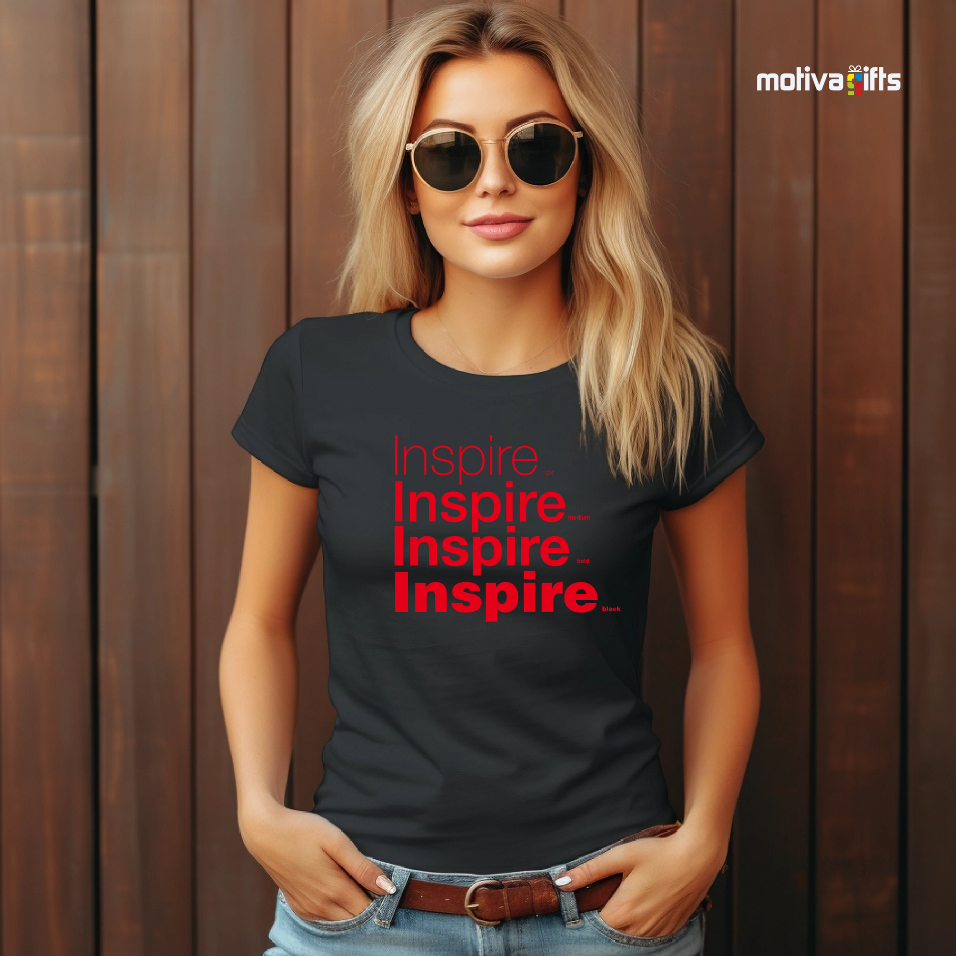  Woman using Black unisex t-shirt with Inspire printed in red on the front in four lines with different font weights (light, medium, bold, black). Made of cotton and polyester, short sleeves, crewneck. By Motiva Gifts.