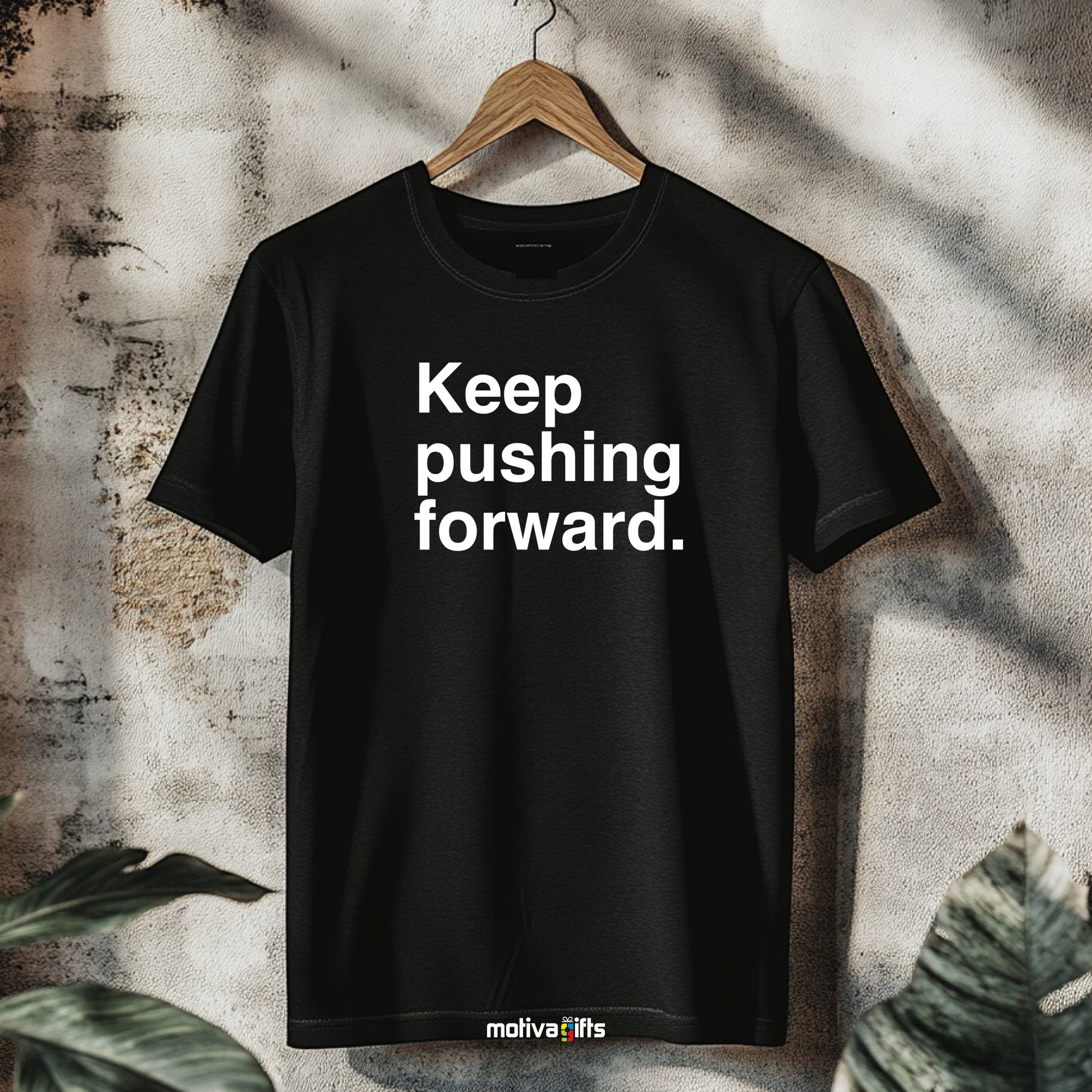 A hanging black T-shirt featuring bold white typography that reads Keep pushing forward 