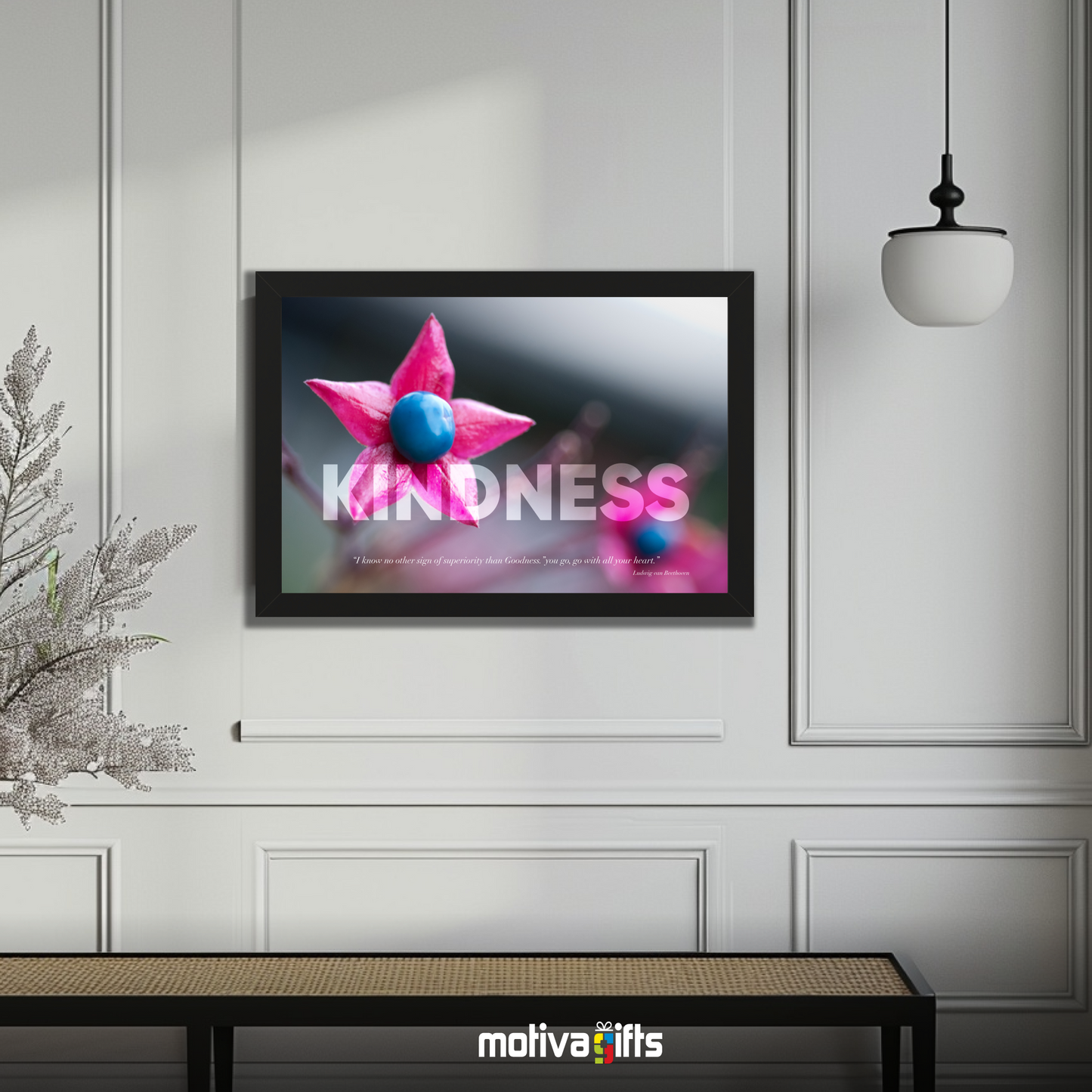 A black framed art wall with the word KINDNESS in large text and Beethoven quote hangs in a modern living room. 