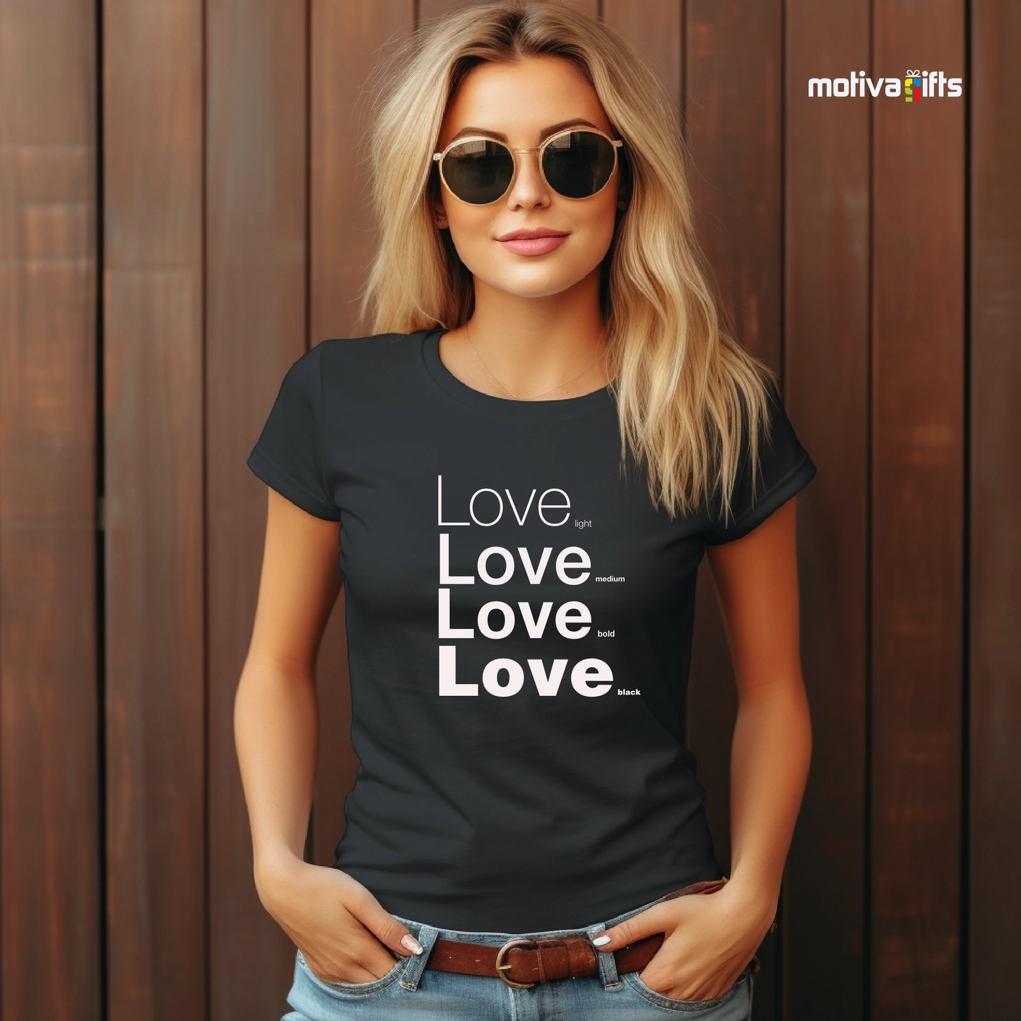 Woman using black unisex t-shirt with Love printed in white on the front in four lines with different font weights (light, medium, bold, black). Made of cotton and polyester, short sleeves, crew neck. By Motiva Gifts.