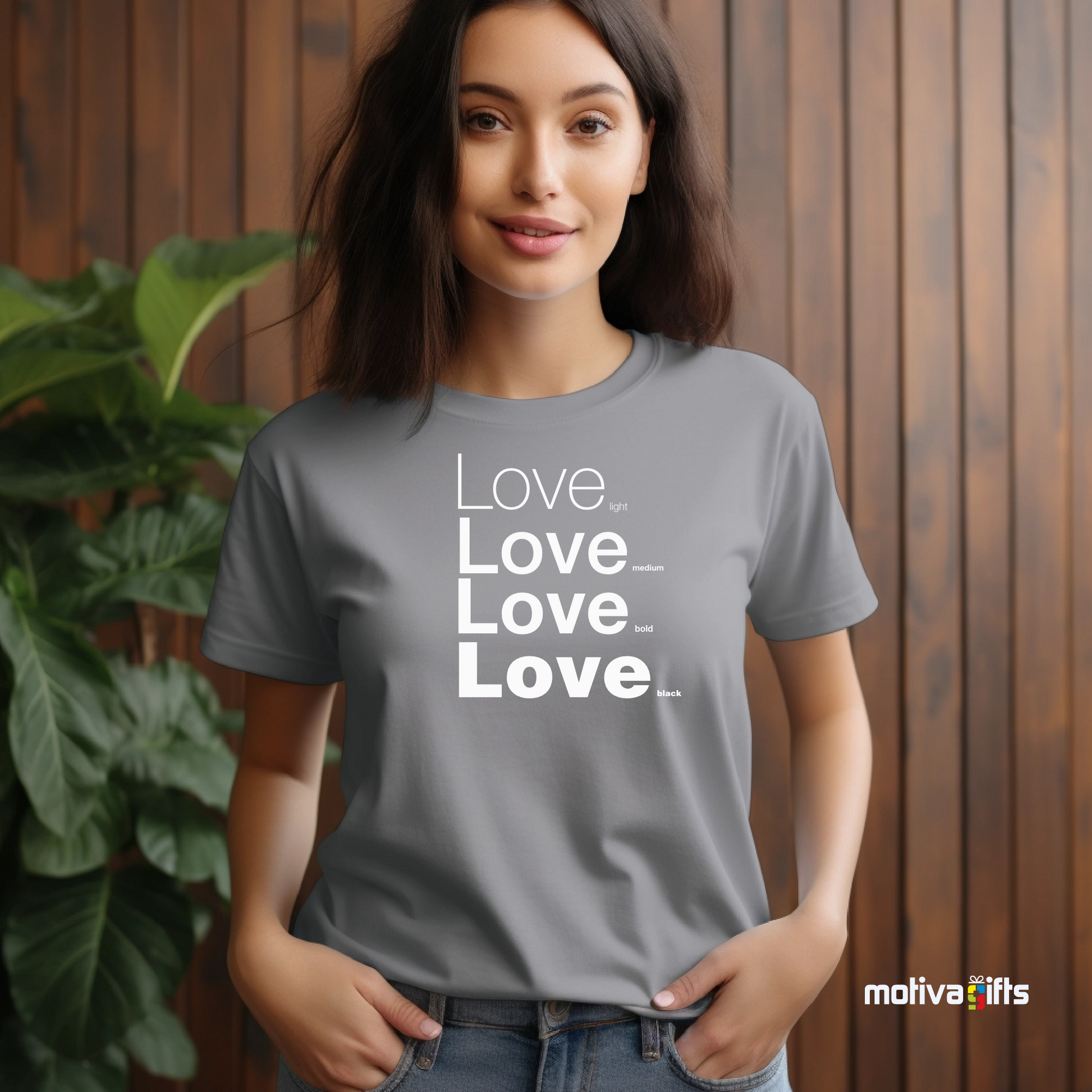 Woman using sport gray unisex t-shirt with Love printed in white on the front in four lines with different font weights (light, medium, bold, black). Made of cotton and polyester, short sleeves, crew neck. By Motiva Gifts.