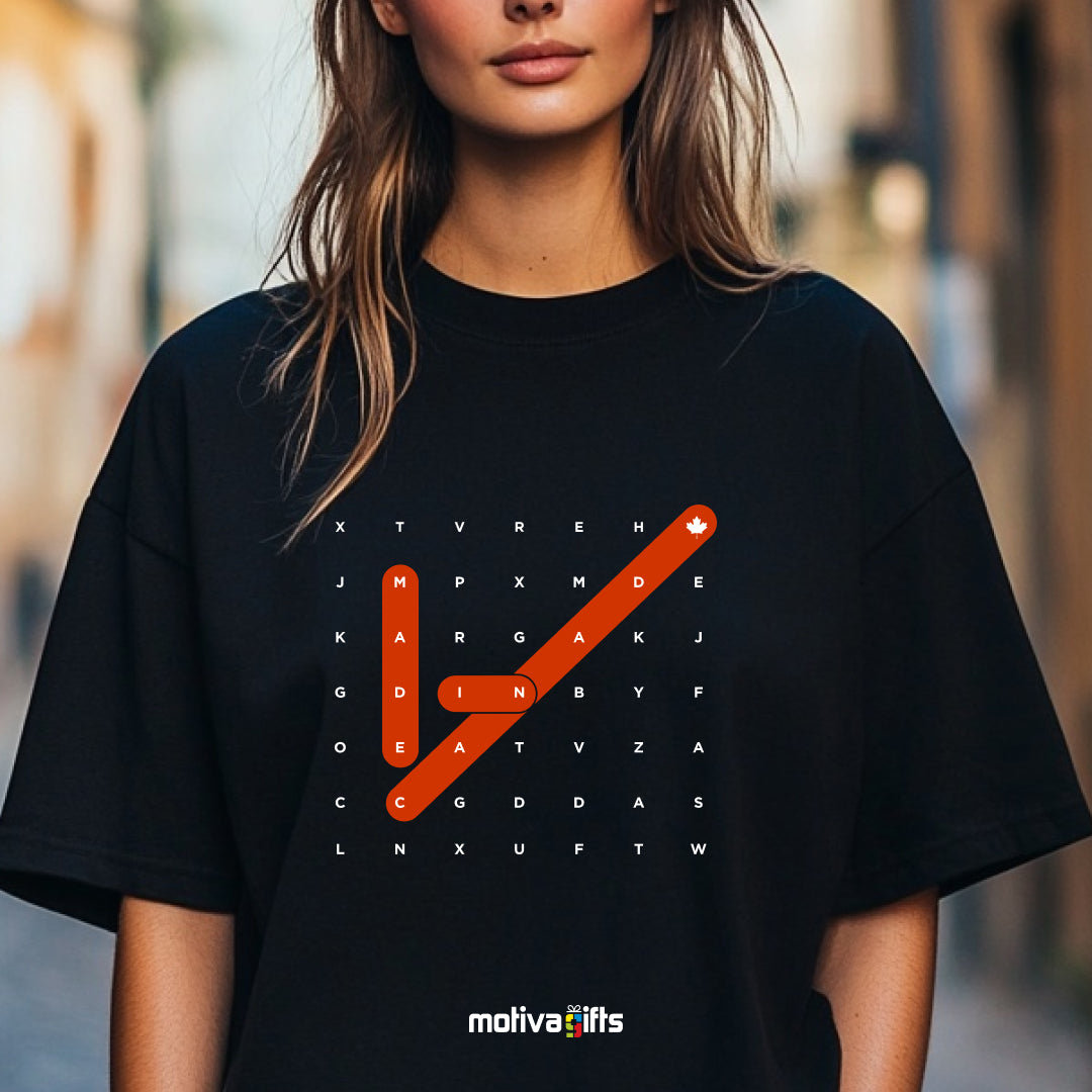 A woman wearing a black T-shirt featuring bold white and red typography that reads Made in Canada Crossword