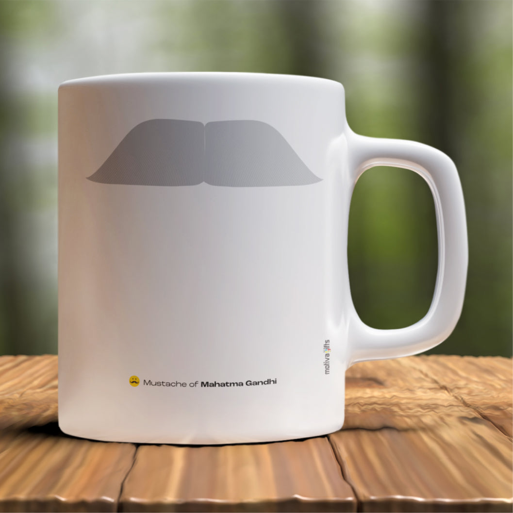 White ceramic mug with a drawing of Mahatma Gandhi’s mustache featuring a rustic table. 