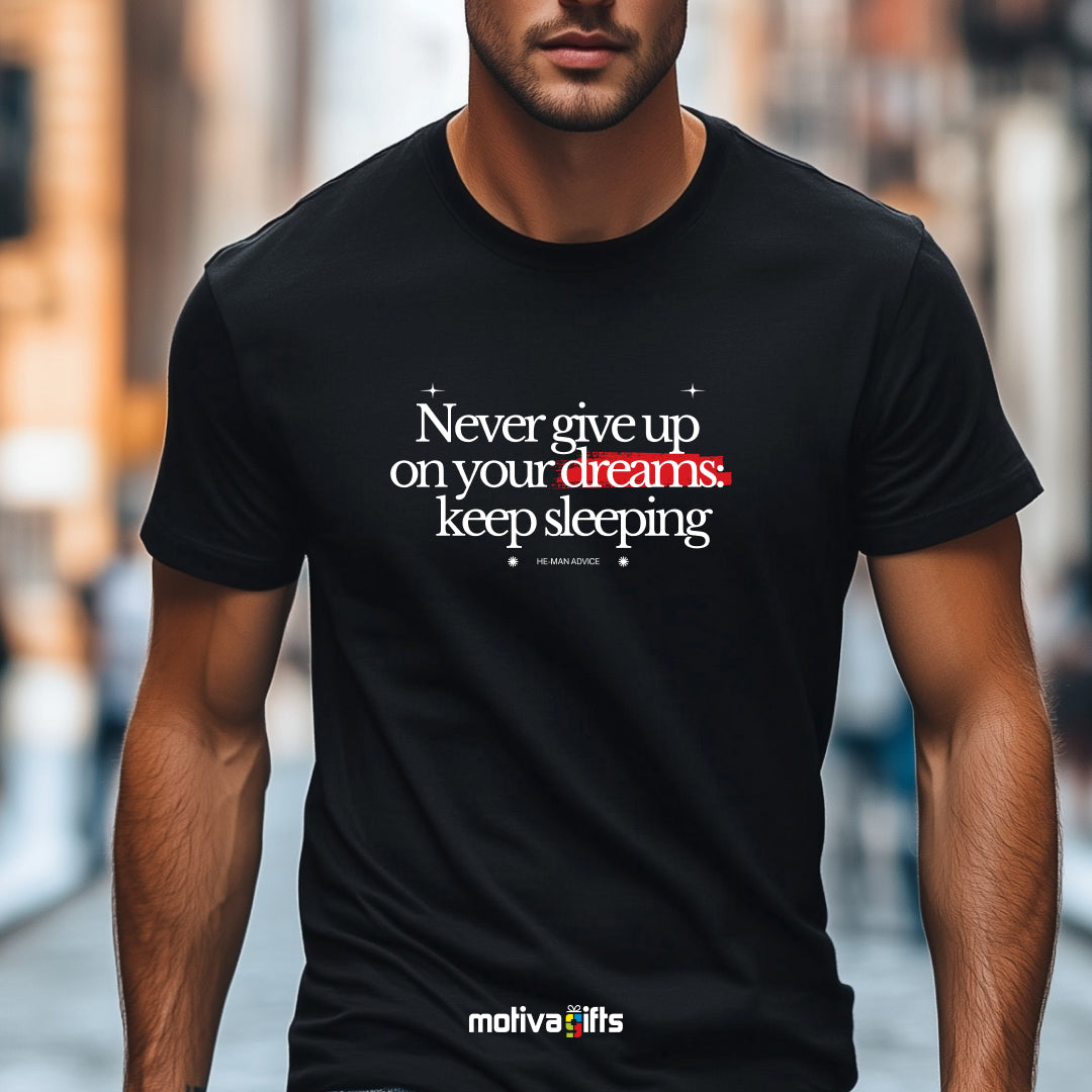 A man wearing a black flat-lay T-shirt featuring white typography that reads Never give up on your dreams: keep sleeping