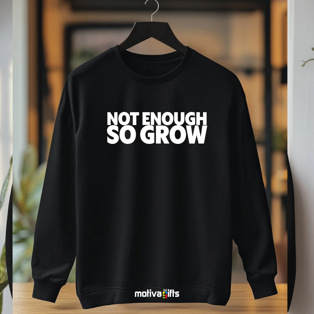 A hanging wearing a black flat-lay Sweatshirt with white typography that reads Not Enough So Grow