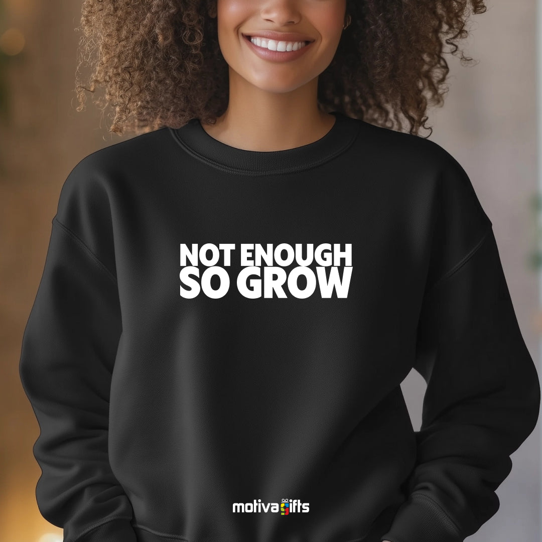 A woman wearing a black flat-lay Sweatshirt with white typography that reads Not Enough So Grow