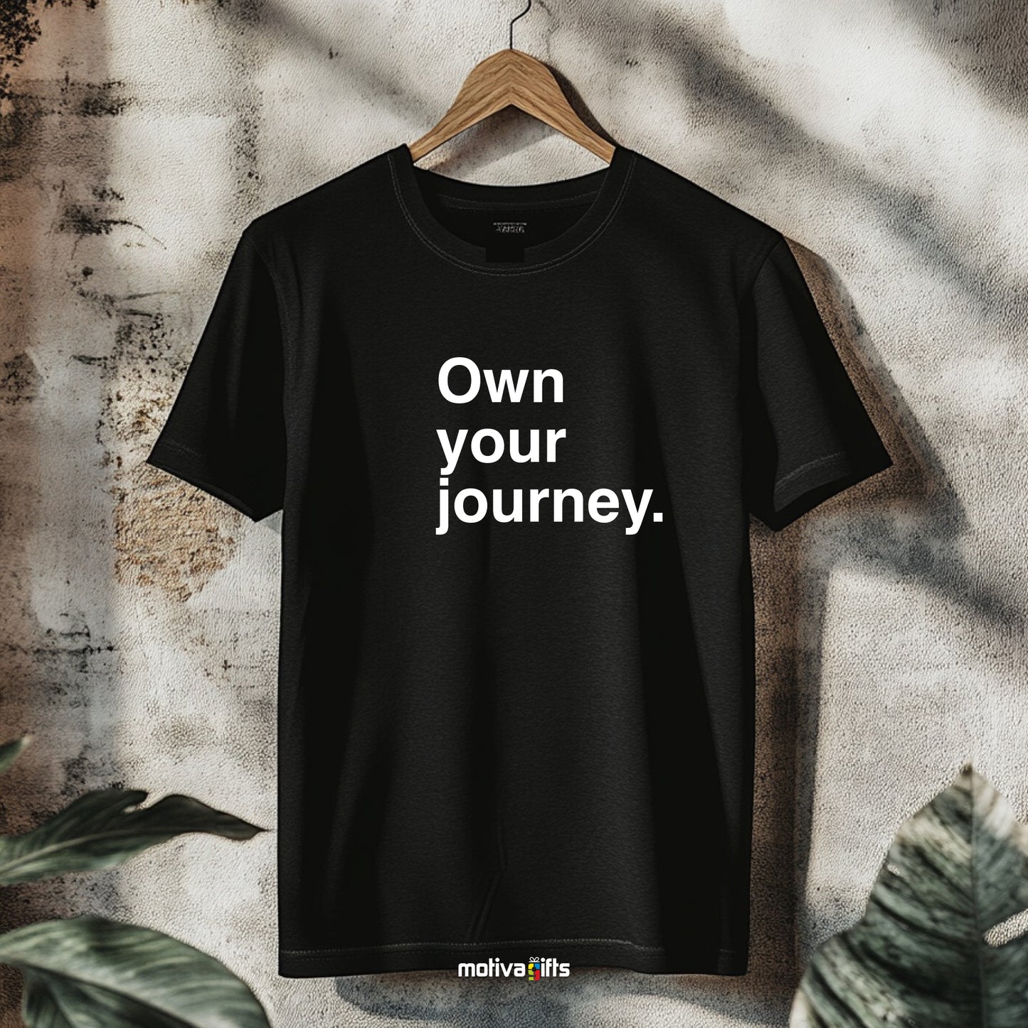  Hanging black T-shirt featuring bold white typography that reads Own your journey  