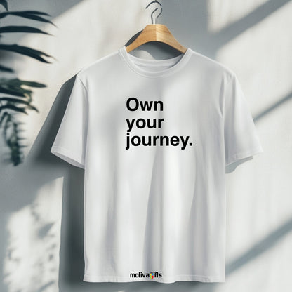 Hanging white T-shirt featuring bold black typography that reads Own your journey  