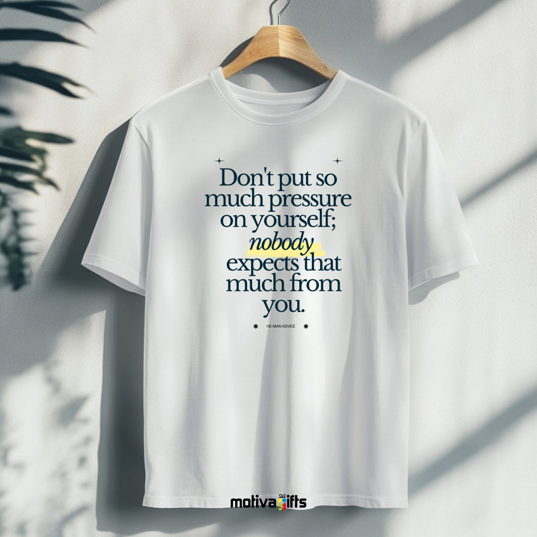 A hanging white T-shirt featuring bold black typography that reads Don’t put so much pressure on yourself; nobody expects that much from you