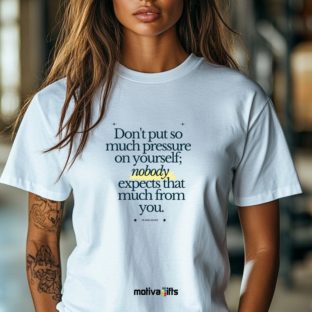 A woman wearing a white T-shirt featuring bold black typography that reads Don’t put so much pressure on yourself; nobody expects that much from you