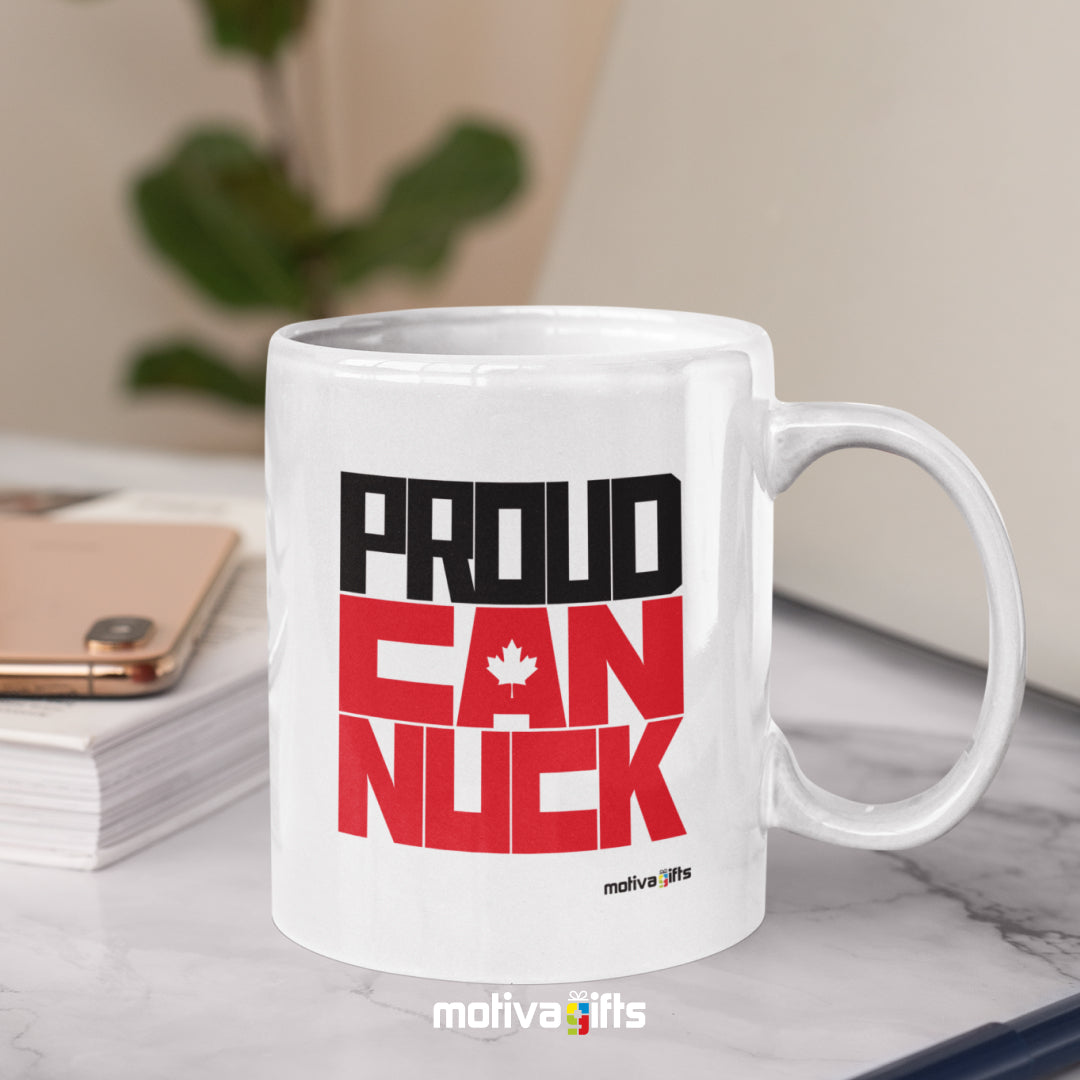 Proud Canuck reads in black/Red bold letters on a white 11 oz ceramic mug, featuring a white table.