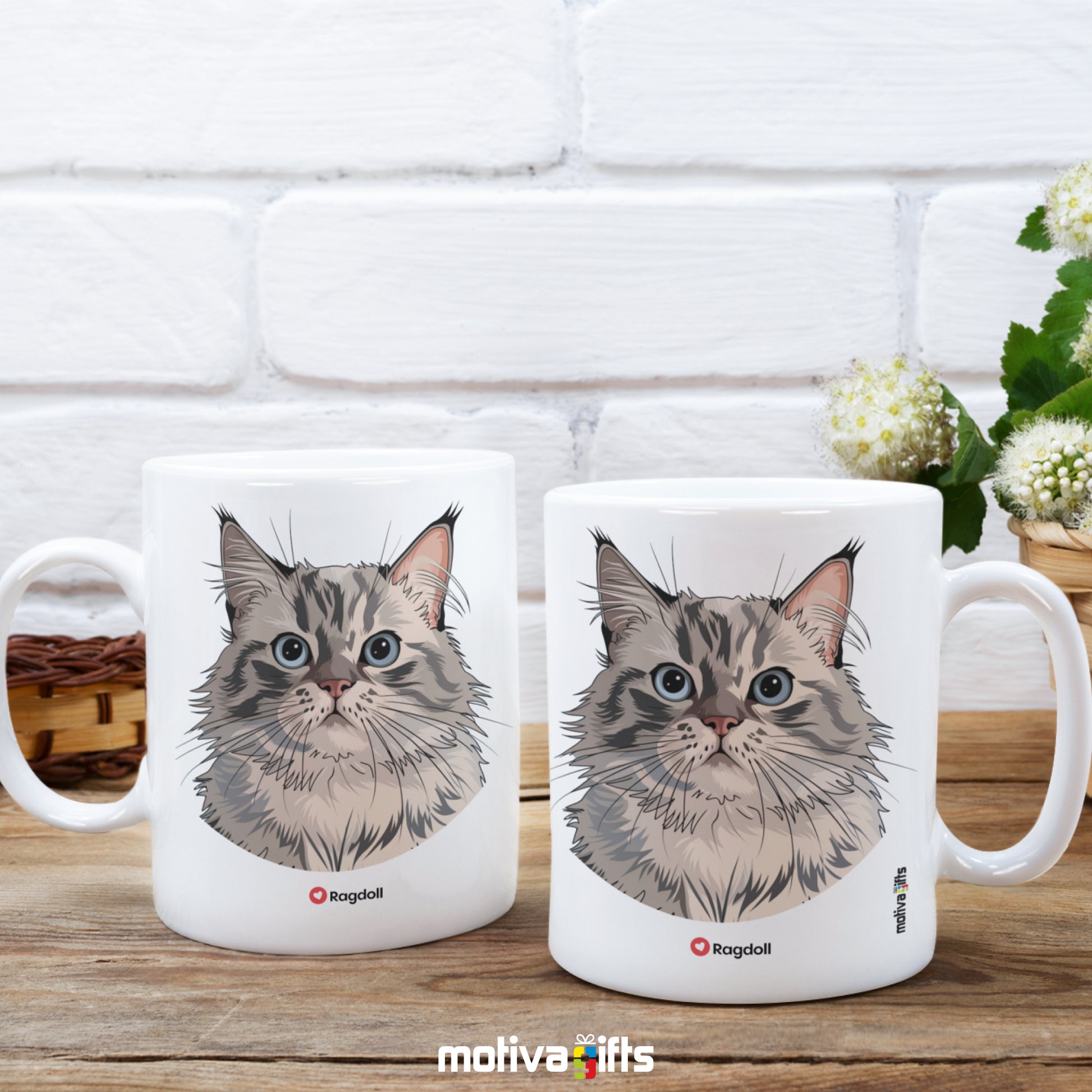 Two mugs, front and back views, of a white 11oz ceramic mug featuring Ragdoll cat love art placed next to a flower basket. 