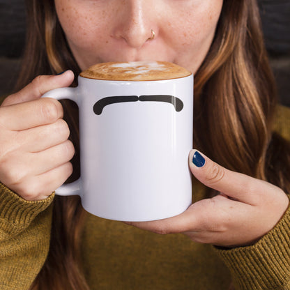 Woman holding a white ceramic mug with a drawing of Ringo Starr mustache