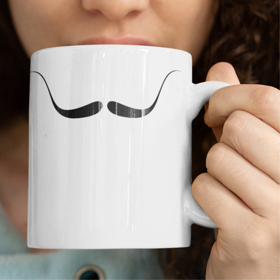 Woman holding a white ceramic mug with a drawing of Salvador Dali's mustache