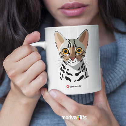 A woman holding a white 11oz ceramic mug featuring Savannah cat love art printed on both sides