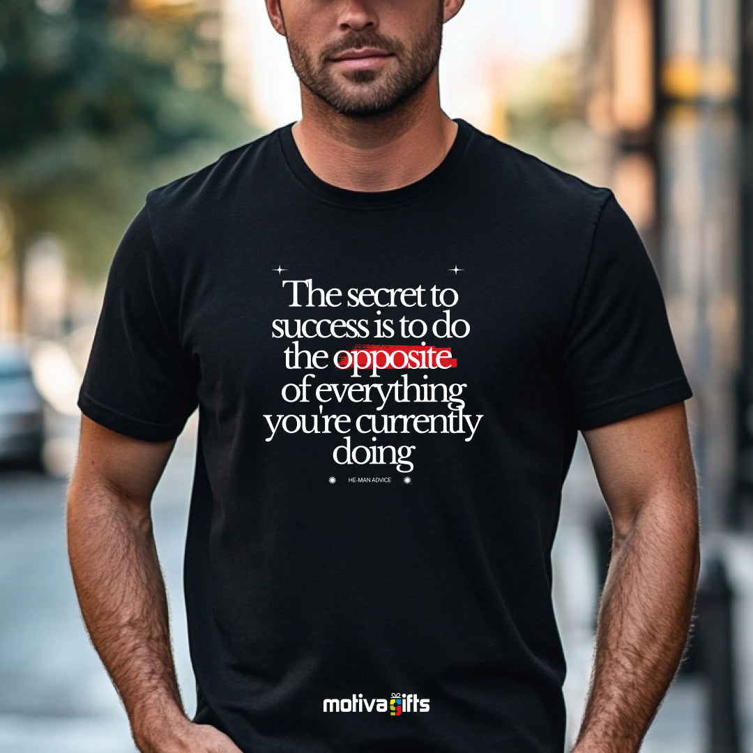 A man wearing a black T-shirt featuring white typography that reads The secret to success is to do the opposite of everything you’re currently doing