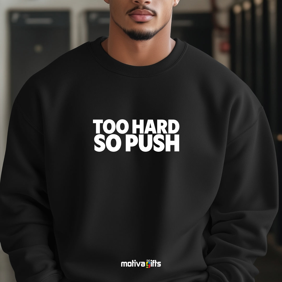 A man wearing a black flat-lay Sweatshirt with white typography that reads Too Hard So Push