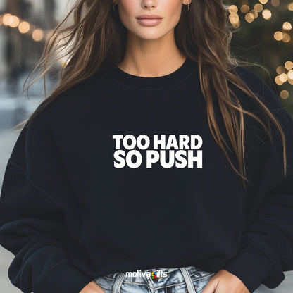 A woman wearing a black flat-lay Sweatshirt with white typography that reads Too Hard So Push