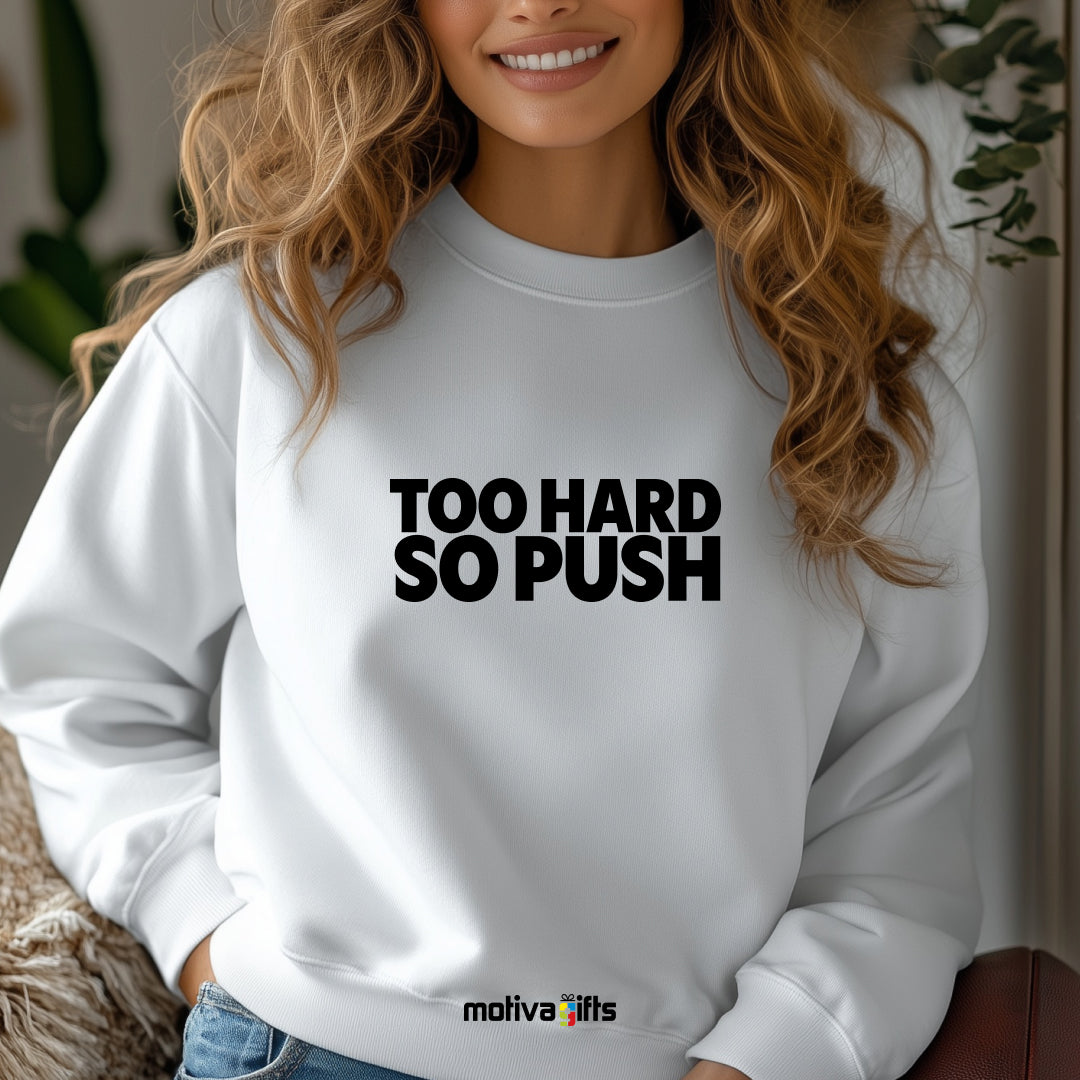 A woman wearing a white flat-lay Sweatshirt with black typography that reads Too Hard So Push