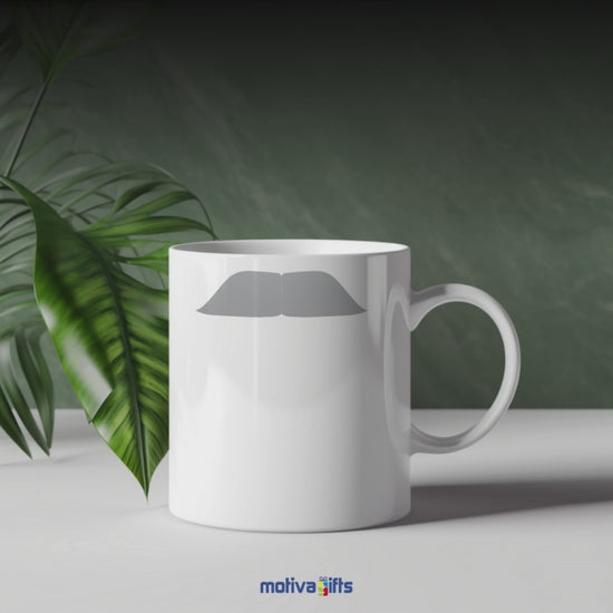 A video shows a mug with a gray mustache design, resembling Mahatma Gandhi Einstein, from various angles and perspectives.